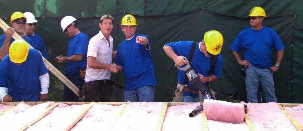 male workers in blue shirts and yellow hard hats working on frames